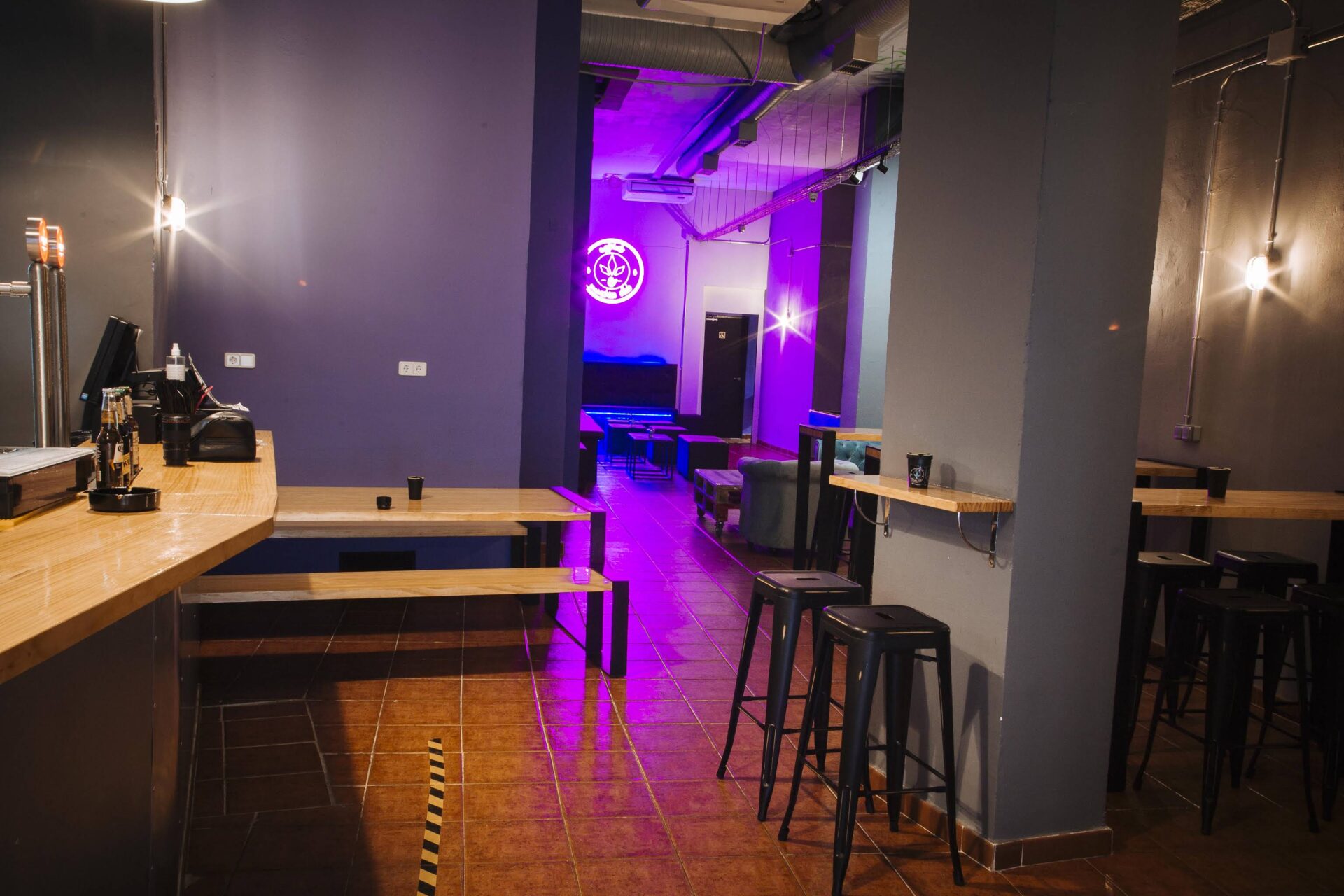Bar- und Sitzbereich im Cannabis-Club Enjoint in Madrid mit Neonbeleuchtung
