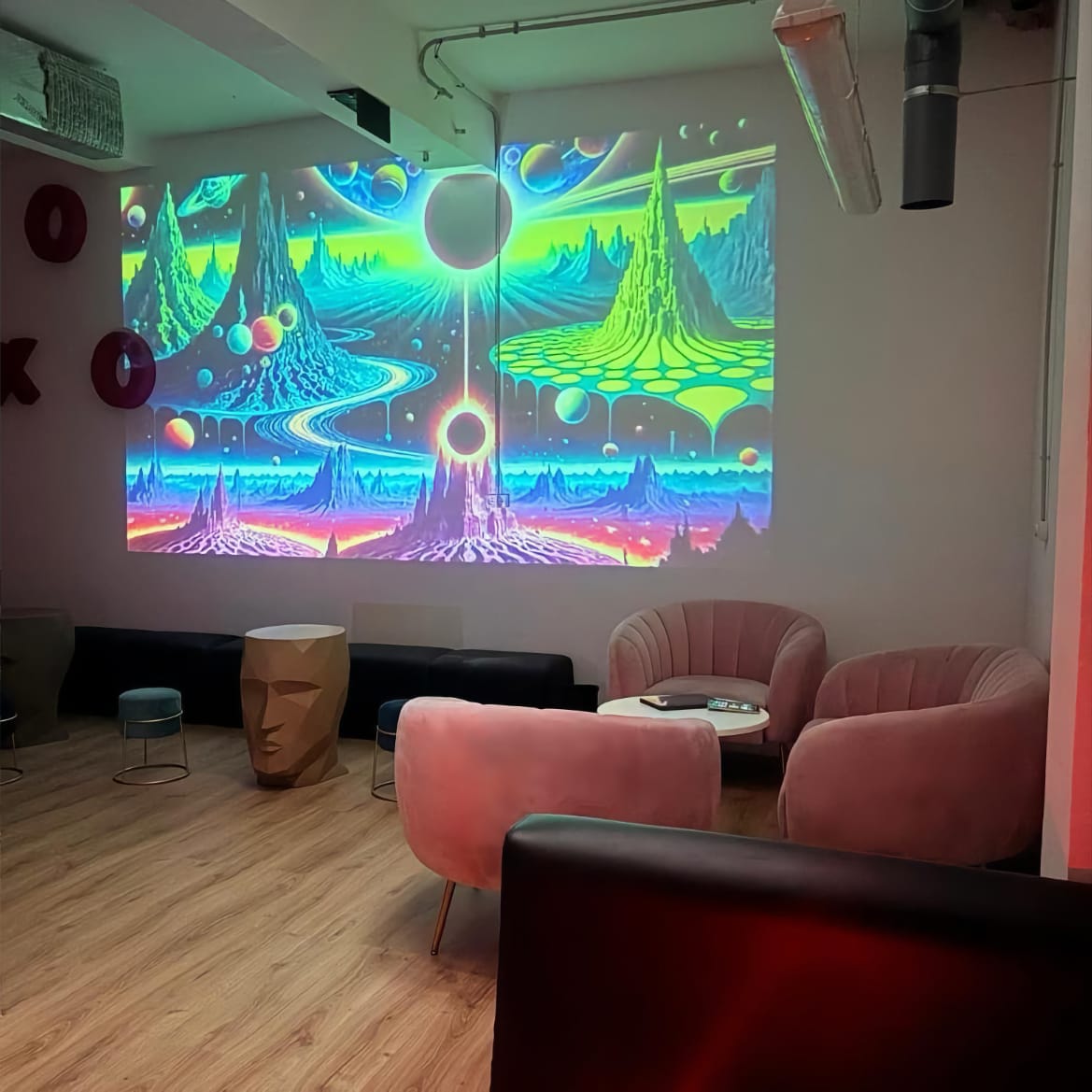 Loungebereich mit Samtsesseln und großer psychedelischer Wandprojektion im Mística Social Club Madrid