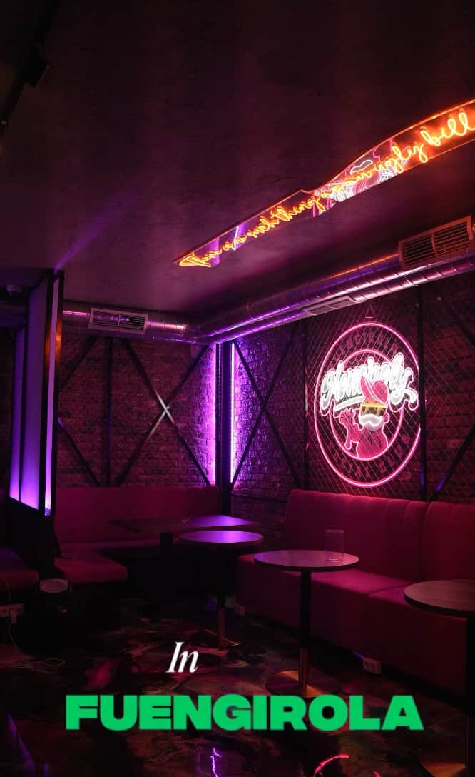 Video-Preview des Monopoly Social Club in Malaga, Lounge mit pinker Ambientebeleuchtung, Ziegelwand, runden Tischen und pink gepolsterten Sofas.  