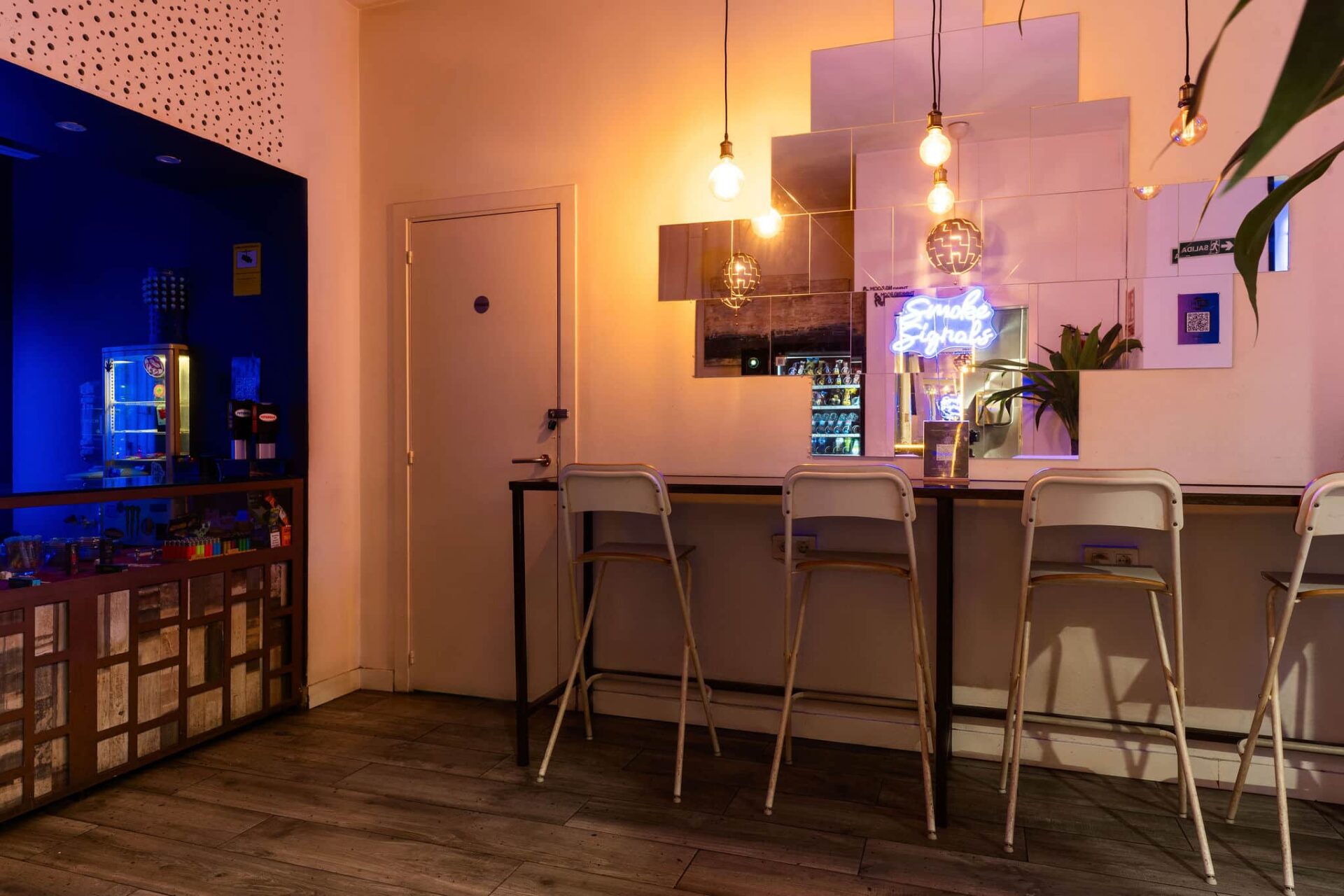 Bartresen mit Spiegeln und Neonzeichen im Smoke Signals cannabis-club Barcelona